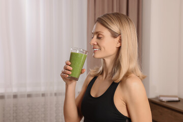 Poster - Young woman in sportswear with glass of fresh smoothie at home