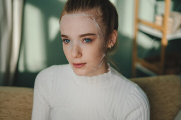 Wall Mural - portrait of a woman with blue eyes having sheet mask on the face for moisturizing, sensual face. bea