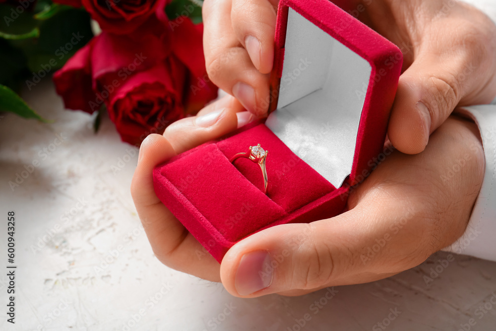 Man holding box with engagement ring on white background, closeup