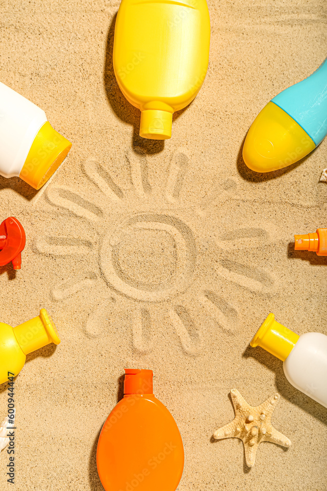 Creative composition with frame made of different sunscreen creams on sand