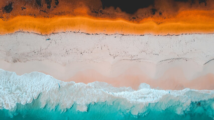 Wall Mural - Aerial view of where the river meets the sea. Vibrant orange and dark river meet turquoise sea waves on beach in Western Australian town called Guilderton.