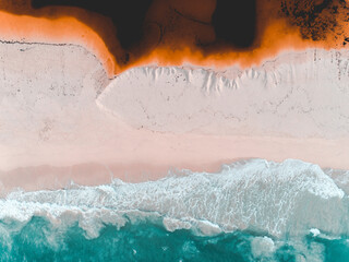 Wall Mural - Aerial view of where the river meets the sea. Vibrant orange and dark river meet turquoise sea waves on beach in Western Australian town called Guilderton.