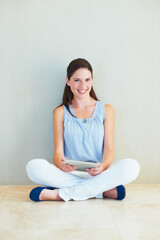 Wall Mural - Portrait, tablet and a woman sitting legs crossed on the floor of her home browsing social media with a smile. Happy, technology and app with a young female person using the internet against a wall