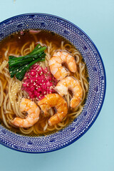 Wall Mural - Portion of ramen noodle soup with shrimp on blue background