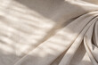 Aesthetic natural textile background with abstract sunlight shadow, neutral beige linen draped fabric, copy space