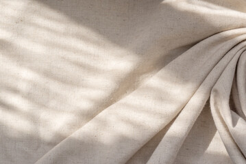 aesthetic natural textile background with abstract sunlight shadow, neutral beige linen draped fabri