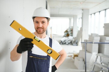 Wall Mural - Portrait of positive, handsome young male builder in hard hat.