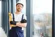 © Serhii - Workman in overalls installing or adjusting plastic windows in the living room at home
