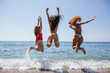 Backview of friends jumping on the water of the beach