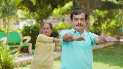 Wall Mural - Indian senior couple doing yoga or stretching at park during morning - concept of active lifestyle, training session and fitness routine