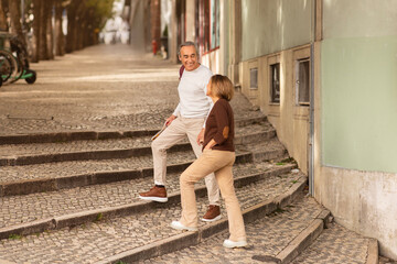 Wall Mural - Cheerful Mature Travelers Couple Walking Through Enchanting Streets Of Lisbon