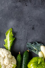 Wall Mural - Border of green raw vegetables on black background. Top view of healthy organic food. Copy space