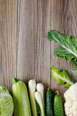 Wall Mural - Border of green raw vegetables on wooden background. Top view of healthy organic food. Copy space