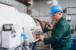 © Vitaliy - Portrait of machine operator wearing hardhat standing at control panel pressing buttons, copy space
