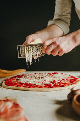 Wall Mural - Close-up of chef preparing pizza grating cheese with a grater