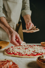 Wall Mural - Close-up of chef preparing pizza putting mushrooms on dough