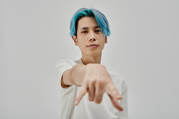 Portrait of Asian stylish teenager with blue hair showing youth gesture on white background