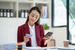 © crizzystudio - Confident Asian businesswomen sitting at their desks Are using banking applications to buy or pay online mobile bills. and registered her credit card on the website for online purchases.