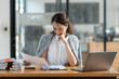 © crizzystudio - Young Asian businesswomen sit stressed out solving various parts of the financial business tasks. administration at her office.
