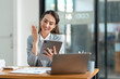 © crizzystudio - Asian businesswoman in a suit sitting holding iPad or tablet in contact See details and discuss business information happily in the office.