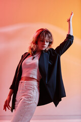 Poster - Vertical image of young female dancer dancing alone against colored neon background