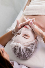 Wall Mural - Woman in moisturizing anti-wrinkle mask. A woman is lying down, resting in a beauty salon. SPA procedures at home or in a cosmetology center