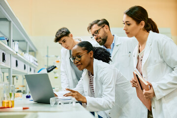 Wall Mural - team of scientist cooperating while analyzing research data on laptop in laboratory.