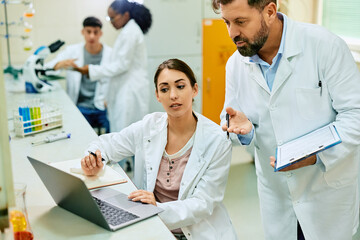 Wall Mural - two scientist cooperating while working on laptop during medical research in laboratory.