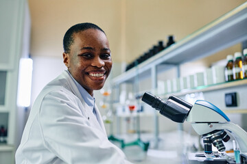 Wall Mural - happy african american biotechnologist working in lab and looking at camera.