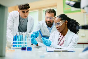 Multiracial team of pharmaceutical experts working on new research in lab.