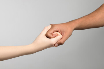 Wall Mural - International relationships. People strongly joining hands on light grey background, closeup