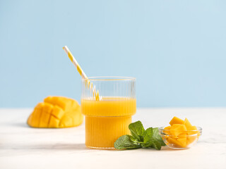 
Mango juice in a glass. tropical juice. Lemonade. Mint leaves. Blue background. Summer drink.