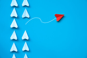 Wall Mural - Top view of red paper airplane origami flying to a different direction leaving other white airplanes on blue background. Leadership and being different concept