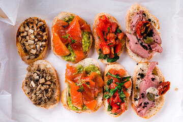 Wall Mural - Set of bruschetta with salmon, avocado, microgreens, tomatoes, mushrooms, onions, meat, capers and sauce.