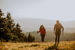 © BGStock72 - Smiling couple walking with backpacks over green hills