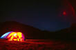 The tourist tent is illuminated by light. Starry sky. Tourism and active recreation. Overnight, camping in the Carpathian mountains, Ukraine. Copy space.