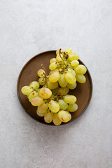 Two bunches of muscat grapes on a brown plate