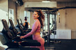 © Zamrznuti tonovi - A happy chubby young sportswoman is walking on a treadmill in a gym and smiling at the camera.