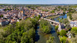 Aerial view of the medieval town of Moret-sur-Loing in Seine et Marne, France - Stone bridge spanning the river Loing towards the Burgundy Gate tower next to Our Lady of the Nativity Church