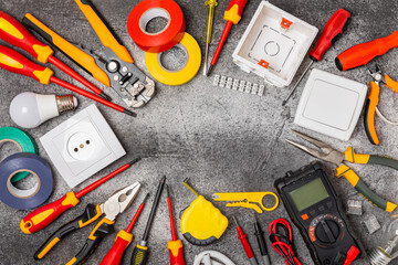 Electrician tools on black marble background.Multimeter,construction tape,electrical tape, screwdrivers,pliers,an automatic insulation stripper, socket and LED lamp.Flatley.electrician concept.