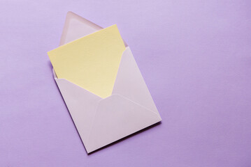 Sticker - Blank greeting card mock up. Beige empty sheet of paper mockup in an violet envelope on violet paper background. flat lay. Wedding, business, birthday still life scene.