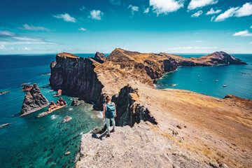 Wall Mural - Athletic woman enjoys the view on rocky cliff from a steep cliff. São Lourenço, Madeira Island, Portugal, Europe.