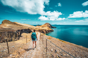 Wall Mural - Sporty woman hikes along hike trail with scenic view on the beautiful foothills of the Madeiran island. São Lourenço, Madeira Island, Portugal, Europe.