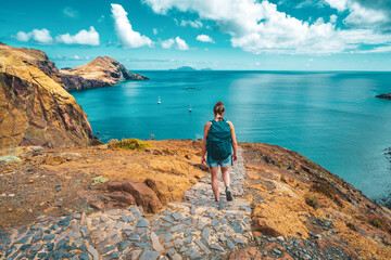 Wall Mural - Sporty woman walking on a paved hiking trail with picturesque view in the beautiful foothills of Madeira Island. São Lourenço, Madeira Island, Portugal, Europe.