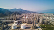 © Gasspoll - Oil refinery with a background of mountains and sky.The factory is located in the middle of nature, Generative AI