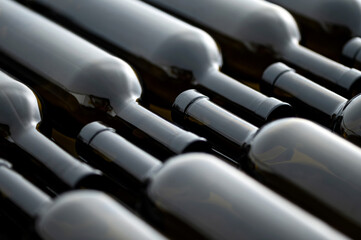 Dark glass wine bottles lie on conveyor belt. Beverage production process. Bottling and packaging of alcoholic beverages. View from above. Close-up. 