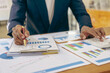 © MrAshi - Business pen points to business documents for data analysis, charts and graphs. Finance and accounting concepts and investment planning for businesses and stocks