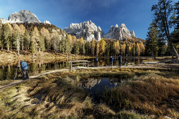 Aufkleber -  Amazing autumn landscape in the mountains with yellow larches and lake glowing by sun and high mountain peaks behind. Antorno lake. Italy. Iconic location for landscape photographers.