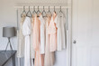 A set of white and pink elegant dresses on black hangers in the wardrobe