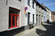 Leuchtend roter Fensterrahmen eines sanierten Wohnhaus als Teil des Unesco Weltkulturerbe bei blauem Himmel und Sonnenschein in den Gassen der Altstadt von Brügge in Westflandern in Belgien